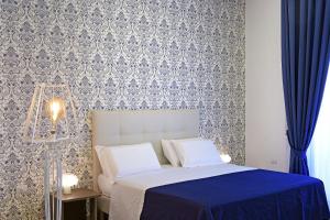 una camera da letto con un letto con carta da parati blu e bianca di Barbarella HOTEL SPA a Napoli