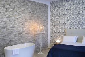 Barbarella HOTEL SPA في نابولي: غرفة نوم مع سرير وحوض استحمام بجانب سرير