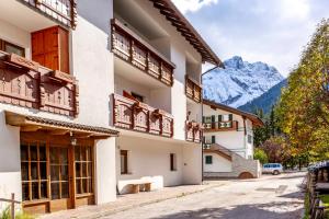 a building with wooden balconies and mountains in the background at Valle Maura in Canazei