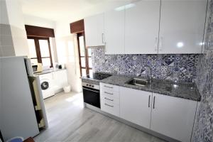 una cocina con armarios blancos y fregadero en T2 Clube Alvor Férias en Alvor