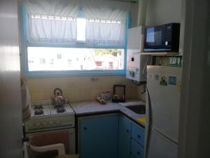 a small kitchen with a refrigerator and a window at DESCANSO IDEAL II CABO CORRIENTES in Mar del Plata