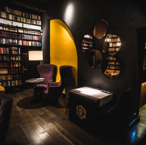 a library with a sink and chairs and books at Apartamenty Siedem Komnat Siedmiu Mistrzów in Toruń