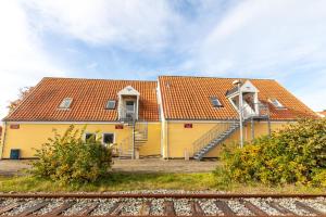 a yellow building with an orange roof next to train tracks at Skråvej Bed & Breakfast in Skagen