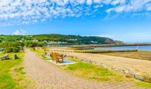 a path along a beach with a bench on it at Staycation at Pine Cottage, a newly refurbished holiday cottage in Goodwick