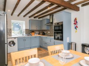 Una cocina con gabinetes azules y una mesa con sillas. en Sea Otter Cottage, en Appin
