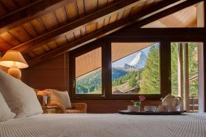 - une chambre avec un lit et une grande fenêtre dans l'établissement Penthouse Zen Zermatt, 100m from Ski Lift and Piste, à Zermatt