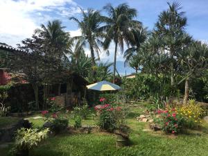 un paraguas en un patio con palmeras y flores en Mundo da lua en Ilha Grande
