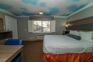 a hotel room with a bed and a window at Hollywood Palms Inns & Suites in Los Angeles