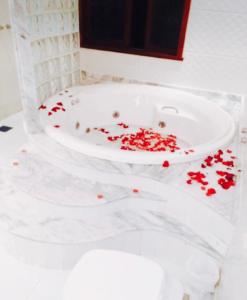 Pousada Jupter في تيريسوبوليس: حوض استحمام أبيض ممتلئ بتلات حمراء