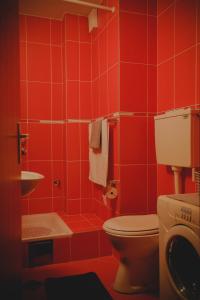 Baño rojo con aseo y lavamanos en Prestige apartment, en Gornji Milanovac