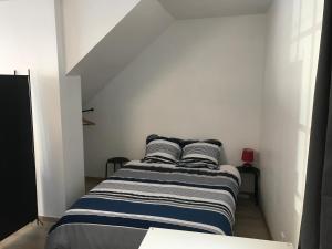 a bed in a white room with two pillows on it at Appartement centre ville in Dole