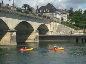 two people in kayaks in the water under a bridge at La Vieille Distillerie in Matha