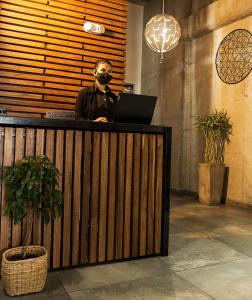 a man wearing a mask standing at a desk with a laptop at The Coffee Club in Manizales