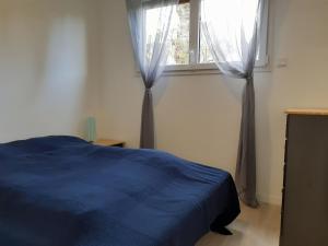 ein Schlafzimmer mit einem blauen Bett und einem Fenster in der Unterkunft L'inattendu du D-Day in Port-en-Bessin-Huppain