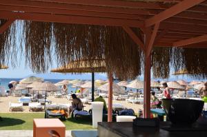 a beach with straw umbrellas and people on the beach at Grand Milano Hotel in Ayvalık