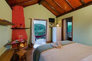 a bedroom with a bed and a fireplace and a balcony at Pousada Lua de Minas in Visconde De Maua +185 photos