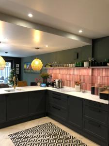 a kitchen with black cabinets and pink tiles at Boutique home near Chichester centre in Chichester