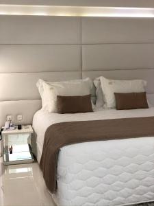 een slaapkamer met een groot wit bed met een hoofdeinde bij Hotel Rieger in Balneário Camboriú