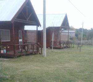 a couple of small wooden buildings in a field at Las Huellas Cabaña in Pehuén-Có