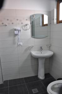uma casa de banho branca com um lavatório e um espelho em VILLA VELA KSAMIL em Ksamil