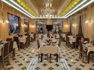 a restaurant with white tables and chairs and a chandelier at Selena in Qusar