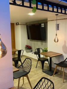 a dining room with tables and chairs and a flat screen tv at Hotel Merlott Lleras in Medellín