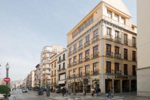een hoog gebouw in een straat met mensen die de straat oversteken bij REYES CATÓLICOS I in Granada