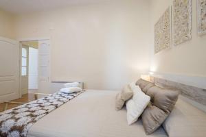 een groot bed in een witte kamer met een bank bij REYES CATÓLICOS I in Granada