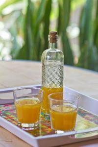 - une bouteille de jus d'orange et deux verres sur un plateau dans l'établissement Gwada Dream, à Sainte-Anne