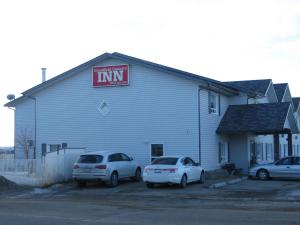 two cars parked in a parking lot in front of a building at Crossfield Country Inn in Crossfield