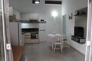 a small white kitchen with a table and a dining room at Residencial Annabel Apto 04 in Bombinhas