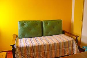Una cama con dos almohadas verdes encima. en EDIFICIO CABO FRIO. I en Pinamar