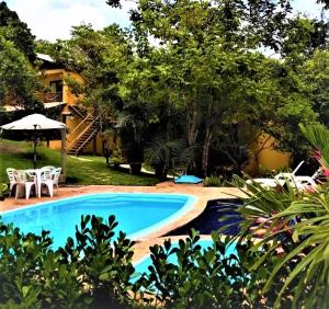 una piscina en un patio con sillas y sombrilla en Vila Hen Praia do Forte - Studios com Varanda e Piscina - Quintas do Castelo da Torre - Reserva Sapiranga - 3,6km da Vila en Praia do Forte