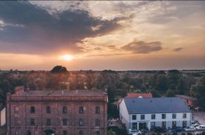 a sunset over an old brick building with the sun in the sky at Hotel Mały Młyn in Stargard