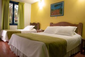 a hotel room with two beds and a window at Ecohotel La Casona Pereira in Pereira