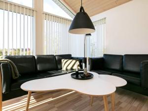 Brovstにある6 person holiday home in Brovstのリビングルーム(黒いソファ、白いテーブル付)