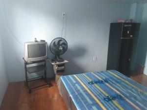 une chambre avec un lit, une télévision et un ventilateur dans l'établissement Suíte Familiar, à Arraial do Cabo