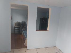 Cette chambre est dotée d'un mur blanc et d'une télévision. dans l'établissement Suíte Familiar, à Arraial do Cabo