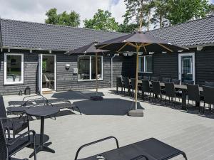 een patio met tafels en stoelen en een parasol bij 22 person holiday home in Nex in Bedegård