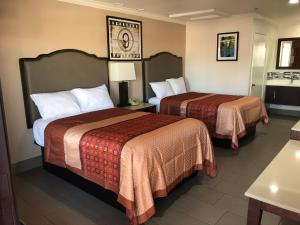 a hotel room with two beds and a table at Economy Inn LAX Inglewood in Inglewood