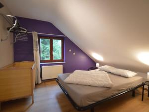 ein Schlafzimmer mit einem Bett und einer lila Wand in der Unterkunft Nice holiday home in Sourbrodt near ski resort in Sourbrodt