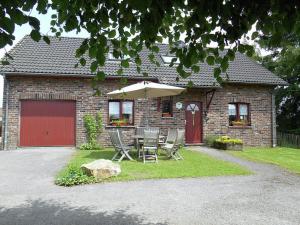 uma casa com uma mesa e cadeiras e um guarda-sol em Nice holiday home in Sourbrodt near ski resort em Sourbrodt