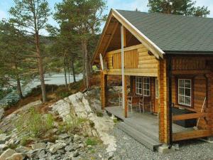 uma cabina de madeira com um deque e uma mesa em Two-Bedroom Holiday home in Vågland 7 em Bårdset