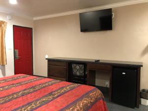 a hotel room with a bed and a flat screen tv at Lotus Motel in Inglewood