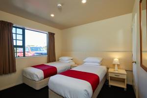 two beds in a hotel room with a window at Lobster Inn Motor Lodge in Kaikoura