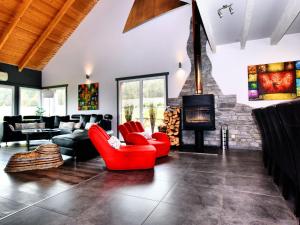a living room with red chairs and a fireplace at Villa with heated outdoor pool and sauna in Manhay