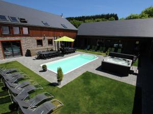 a backyard with a swimming pool and chairs next to a building at Villa with heated outdoor pool and sauna in Manhay