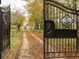 an iron gate with a dirt road behind it at Authentic holiday home with private pool in Puy-lʼÉvêque