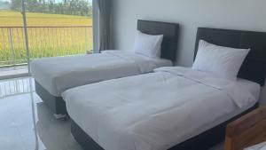 a bed with white sheets and pillows in a bedroom at Beluran Panorama in Tabanan