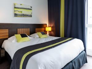 a bedroom with a large white bed with yellow pillows at Lagrange Apart’Hotel Paris-Boulogne in Boulogne-Billancourt
